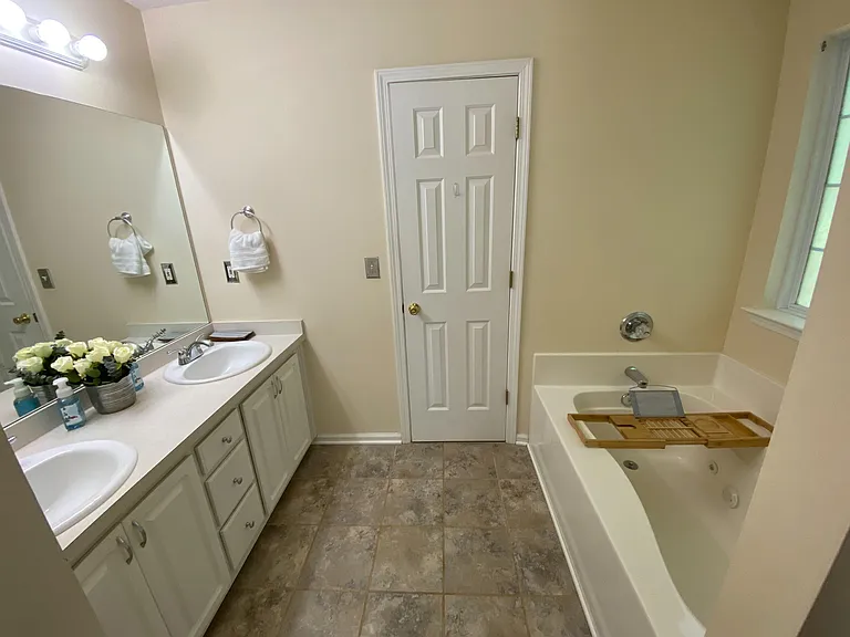 Full bathroom with double-sink vanity, large mirror, and a tub/shower combo, plus a window for natural light.