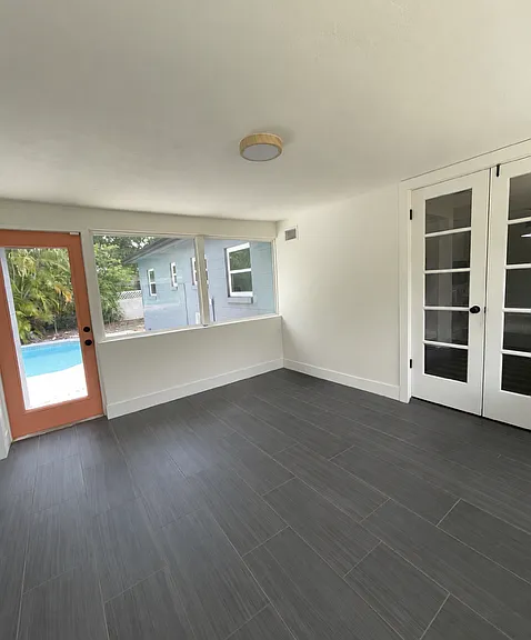 Sunroom overlooking the street and private courtyard pool, ideal for use as an office, media room, or flex space.