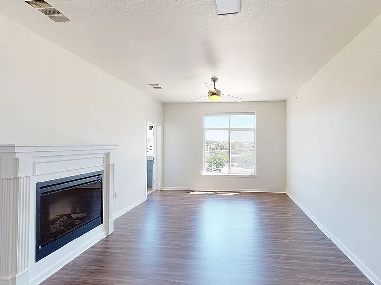 Apartment living room with wood-style flooring, fireplace and patio or balcony in select homes.