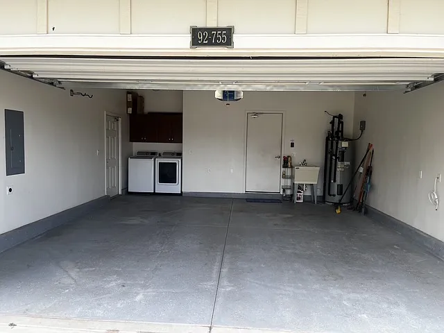 Two car garage with automatic door and EV charging wall plug. Washer and dryer, cabinets, laundry sink and water heater