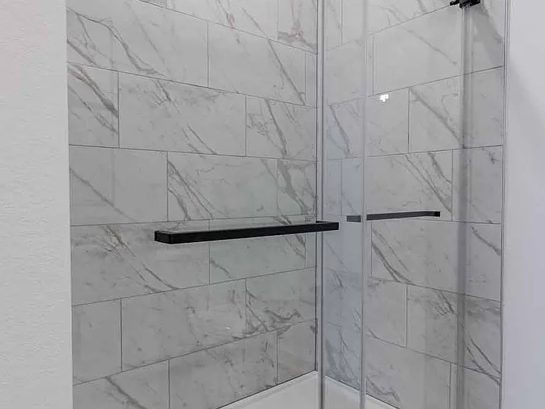 Spa-inspired walk-in shower with marble-style tile, a built-in niche, and a sleek sliding glass door. Spa-inspired walk-in shower with marble-style tile, a built-in niche, and a sleek sliding glass door.
