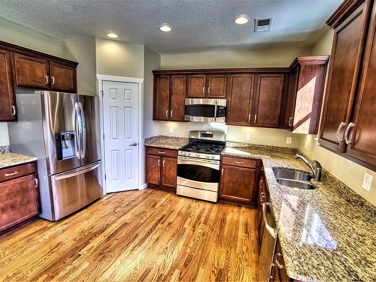 Main level - kitchen w/pantry, like-new stainless steel appliances, under-cabinet lighting, hardwood floors, and granite counter tops (14' x 11').