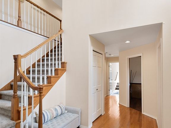 Dramatic two story entry and spindle staircase. The landing separates the primary suite from the other bedrooms and bonus room. Hardwood floors are throughout the entry, kitchen and eat-in area. Open door is the main floor office entry and the powder room is just to the right of the entry.>