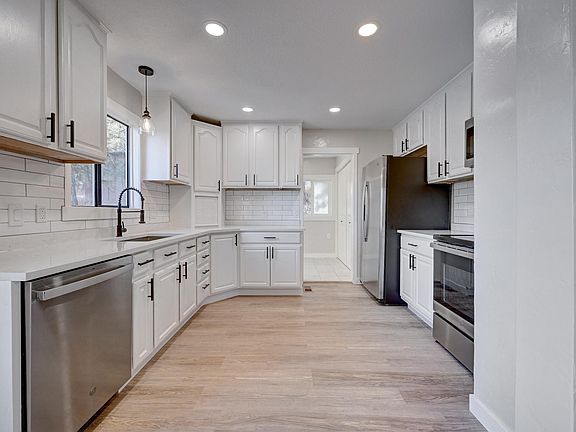 Modern kitchen with new stainless steel appliances and quartz countertops.