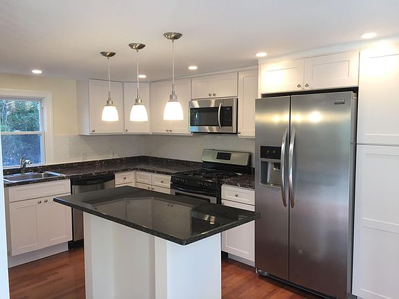 Fully equipped kitchen with shaker white cabinet, granite counter top, center island and stainless steel appliances