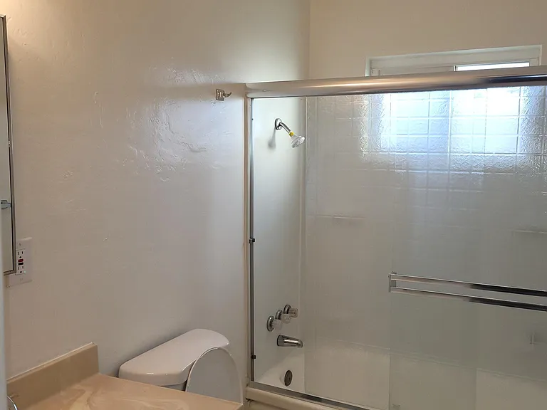 Bathroom with tub/shower combination and glass doors.