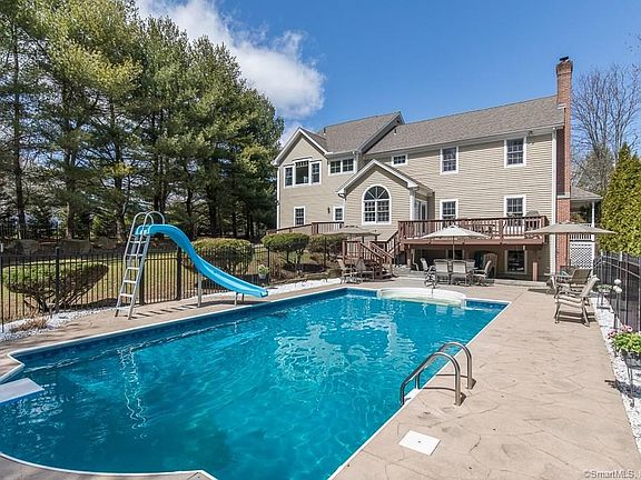 Exterior picture of the back of 8 Punkin Patch Rd and the heated in-ground swimming pool with fencing.