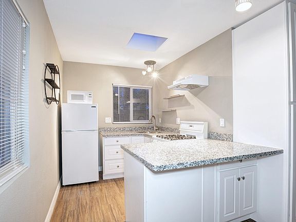 Kitchen with gas range and oven, refrigerator, microwave, under-counter cabinets and floor to ceiling storage. Not pictured: mini-split HVAC unit opposite of cabinets to right.