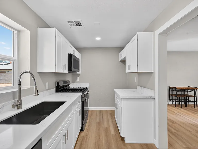 Galley-style kitchen with generous counter space, ample cabinetry, and stainless appliances, opening to an adjacent dining ar