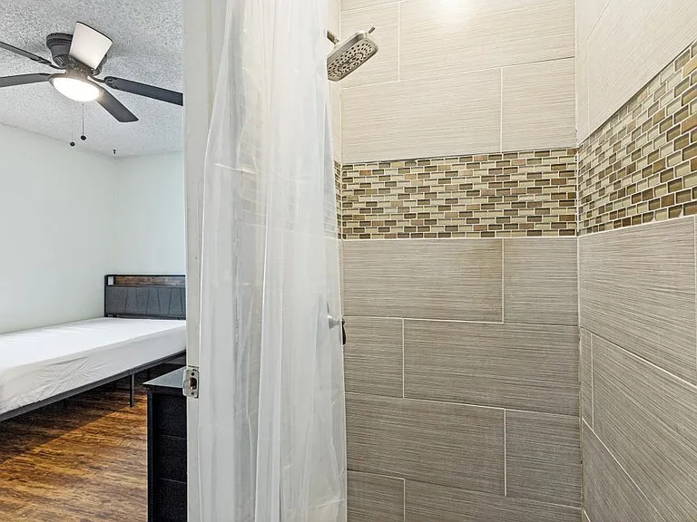 Tiled walk-in shower with rainfall-style showerhead and mosaic accent band for a clean, easy-to-maintain setup.