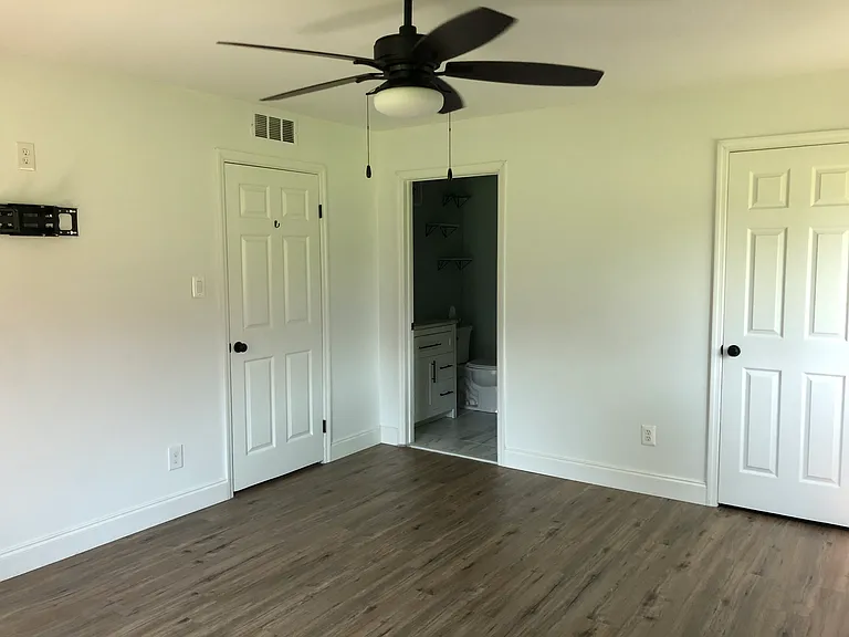 master bedroom with ceiling fan and TV mount