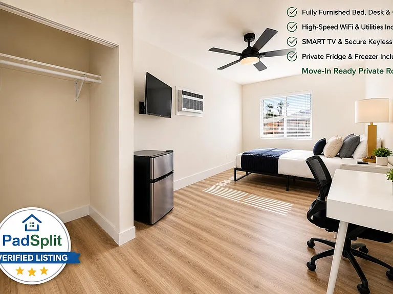 Furnished private bedroom with a bed, desk and chair, wall-mounted TV, mini fridge, ceiling fan, and an open closet.