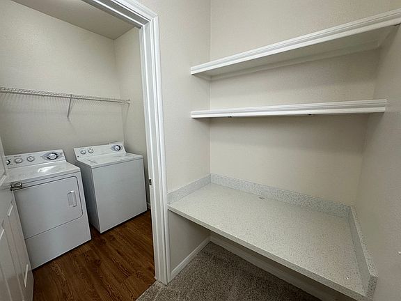 Office nook and modern laundry room with washing machine, dryer, and ample shelving space for storage. Office nook and modern laundry room with washing machine, dryer, and ample shelving space for storage.