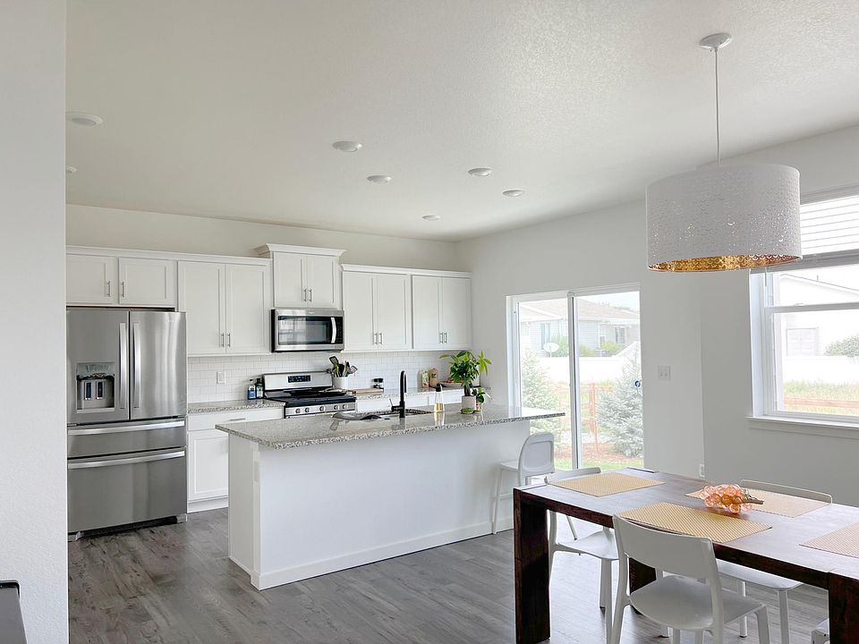 Open concept kitchen/dining/living room space. View from dining room to kitchen. Kitchen opens to back yard, which backs up to open space.