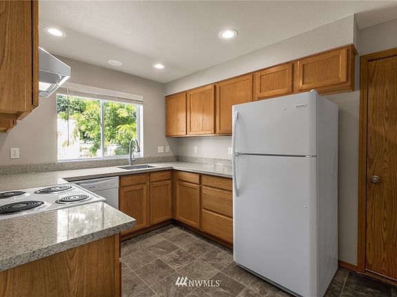 The cheerful kitchen offers an efficient design, new quartz counters, undermount stainless sink, and new appliances.