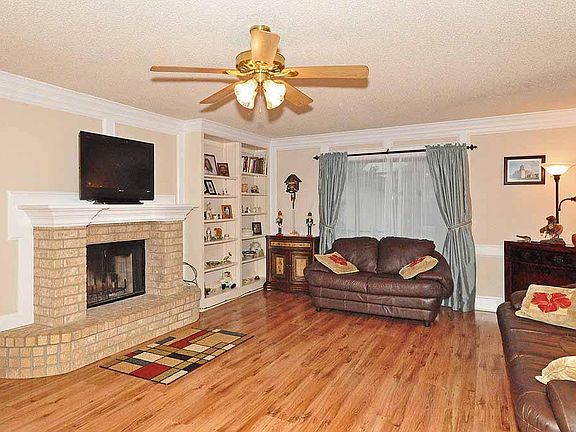 Welcoming living room with laminate flooring, fireplace and built in shelves.