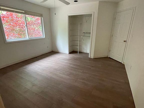 Bedroom with ceiling fan, closet, and view of tree out the window