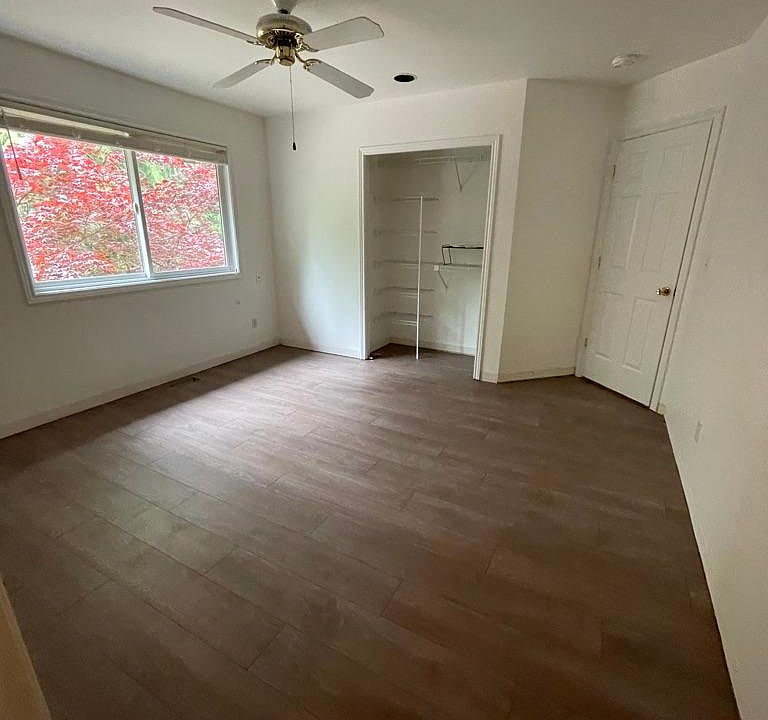 Bedroom with ceiling fan, closet, and view of tree out the window
