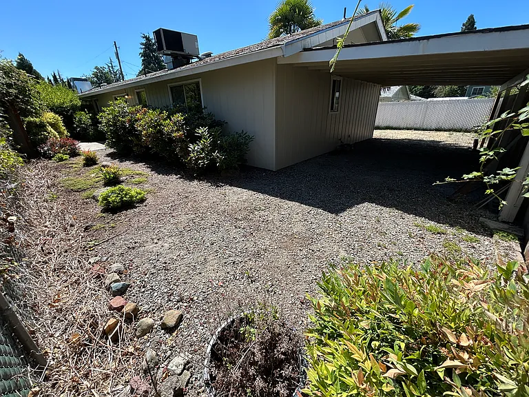Backyard looking east and showing north end of carport