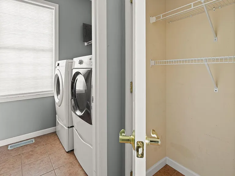 Laundry room and coat closet by entryway to attached 2-car garage with storage.