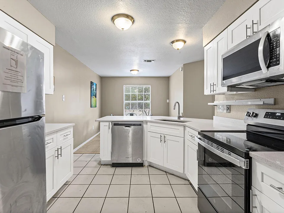 Spacious kitchen with ample white cabinetry, generous counters, and stainless-steel appliances, plus a peninsula for prep.