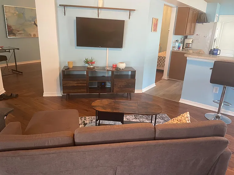 Open-concept living area with sectional seating, wall-mounted TV, and easy flow to the kitchen breakfast bar.