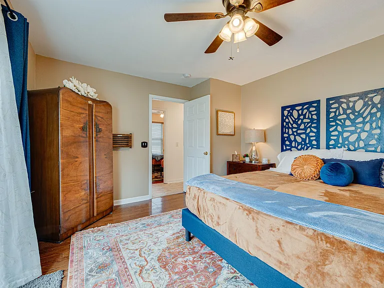 Back bedroom with plush King bed, vintage Gentleman's cabinet, ceiling fan, blackout curtains