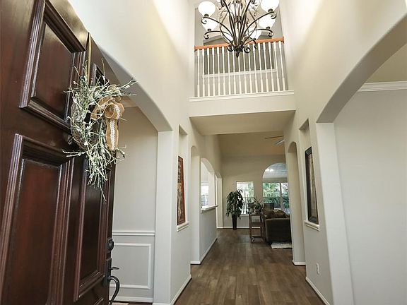Stunning two story entrance with elegant chandelier and wood look tile floors. All of the home has 10/2020 interior paint.