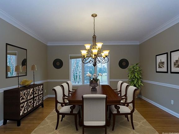 Virtually staged formal dining room with crown molding, chair rail and hardwood floors