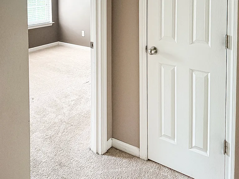 Hallway view into second bedroom and hall linen closet