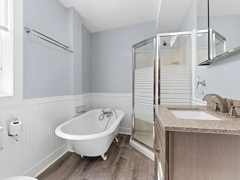 The huge bathroom features a claw-foot tub and a shower along with plenty of light.