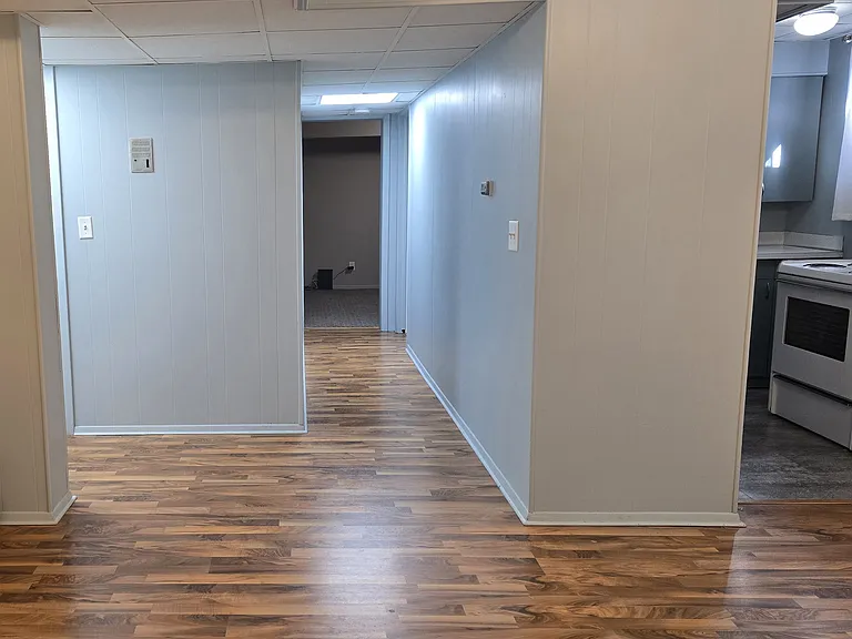 View from living-dining room with entry on the left, kitchen on the right, bathroom and bedroom down the hall