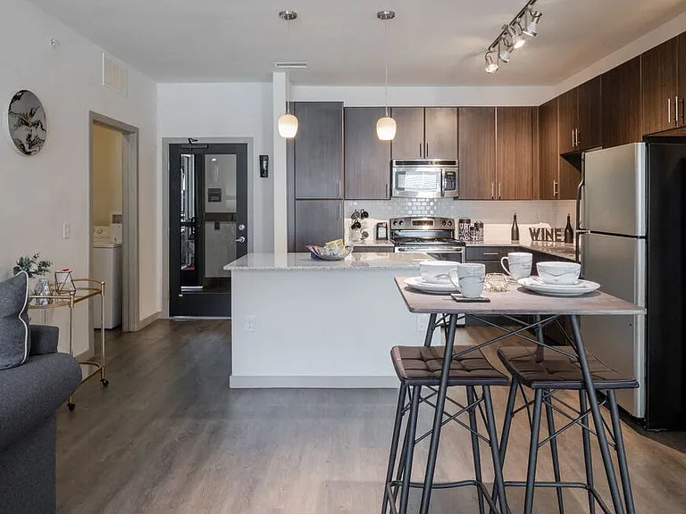 Centro Apartments model kitchen with table, track lights and brown cabinets