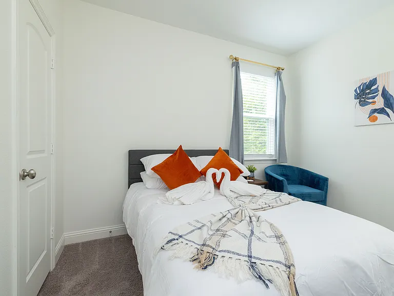 Bedroom 3 features a queen bed, cozy corner chair, plus a desk and chair_ideal for remote work or relaxing in style.