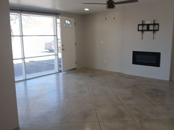 View from the dining room into the living room showing the front door and the large floor ceiling window and also the LED fireplace.