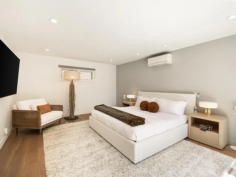 Spacious bedroom equipped with a smart TV, plush lounge chair, and luxurious linens.