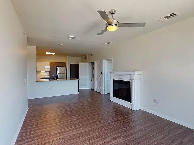 Apartment kitchen with stainless steel appliances, dining and living room with wood-style flooring.