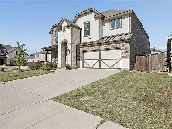 View of front of house featuring a standing seam roof, concrete driveway, brick siding, a metal roof, and a garage