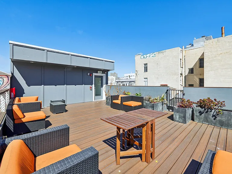 Rooftop patio with lounge chairs, potted plants, and table