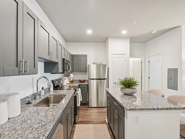 Cook and entertain in style in this modern kitchen featuring gray cabinetry, beautiful granite countertops, and stainless steel appliances.