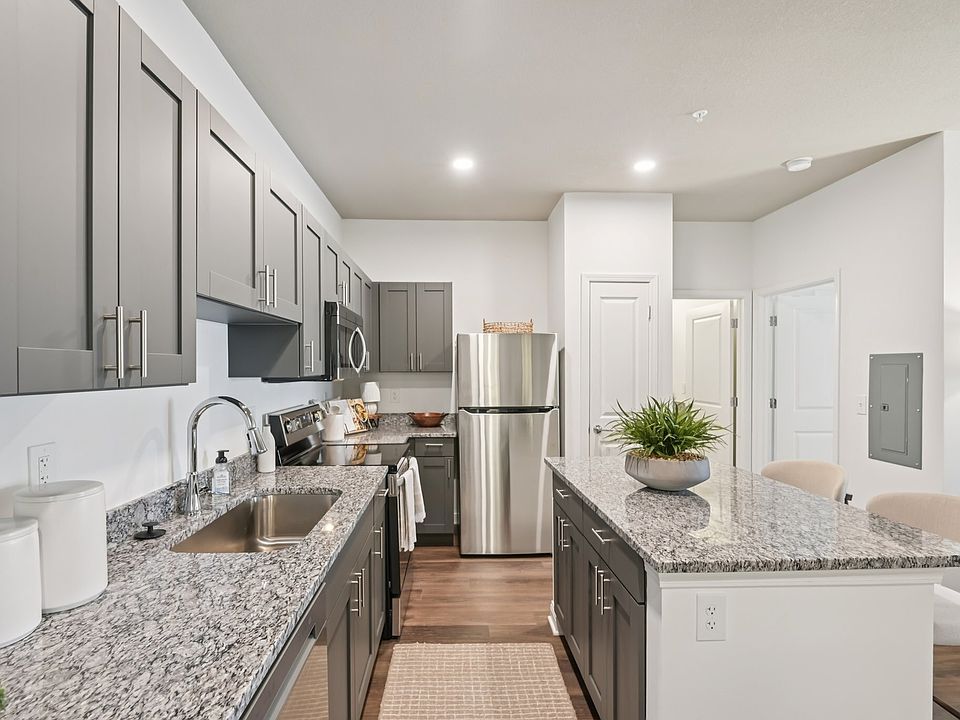 Cook and entertain in style in this modern kitchen featuring gray cabinetry, beautiful granite countertops, and stainless steel appliances.