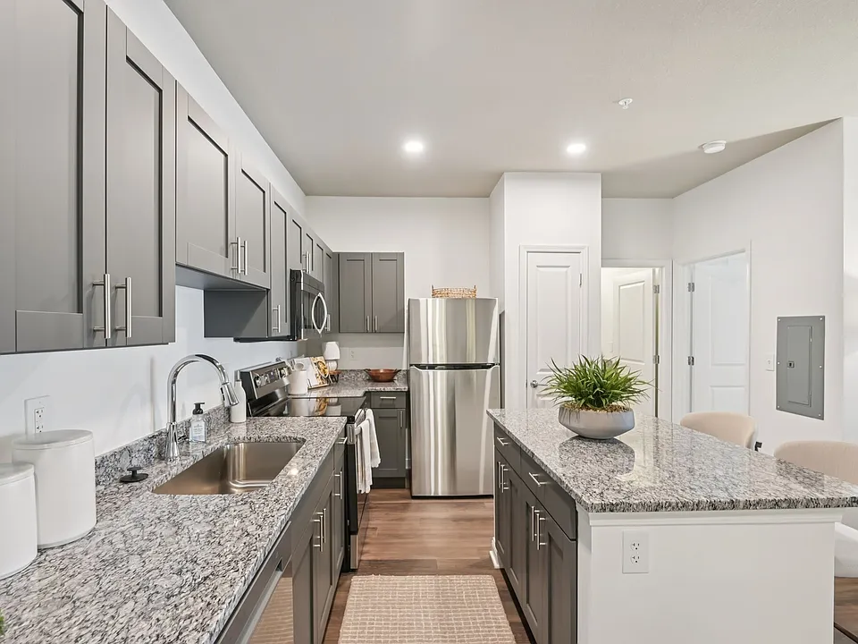 Cook and entertain in style in this modern kitchen featuring gray cabinetry, beautiful granite countertops, and stainless steel appliances.