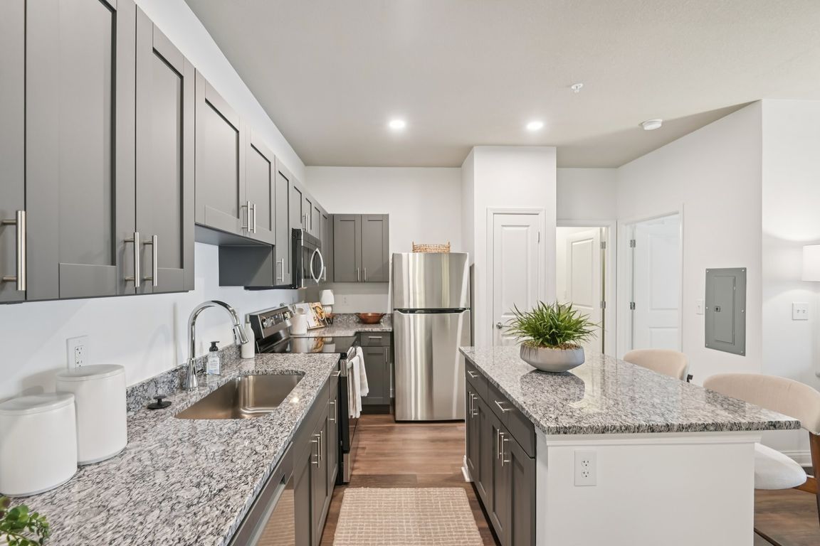 Cook and entertain in style in this modern kitchen featuring gray cabinetry, beautiful granite countertops, and stainless steel appliances.