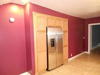 Newer stainless-steel fridge is built into this wall of cupboards with pantry and broom closet.