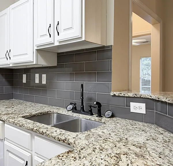 Kitchen features real granite countertops and tile backsplash.