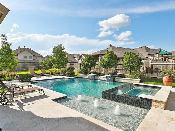 An incredible pool designed and built by Omega Pools: Timeless in design, large hot tub with elevated seating, terrific shallow landing with fountains, three waterfall features, pebble tech surface and lots of beautiful decking for your favorite pool