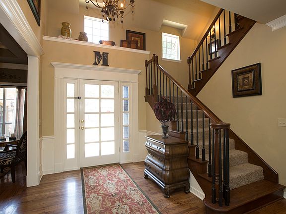 Beautiful Entry greets guests with rich hardwoods, wainscoting, refinished banister, updated paint, elegant chandelier and display ledge.