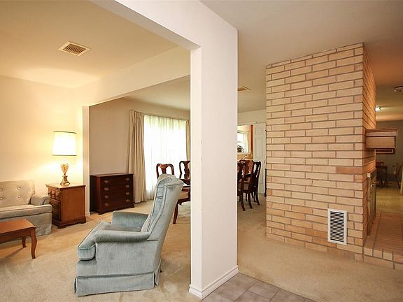 From entry view of formal living, dining and brick fireplace facing family room.