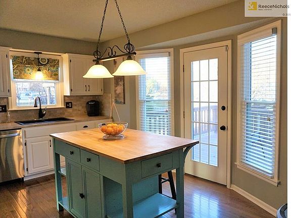 What an adorable kitchen. White cabinets are set off by the turquoise island. Updated lighting, sink, and faucet.