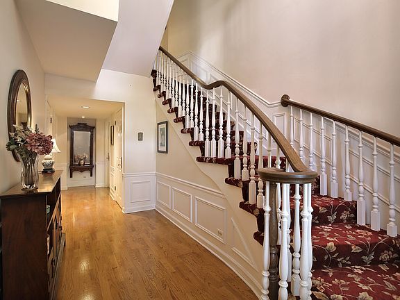 Elegant 2-story foyer with sweeping staircase and hardwood floors